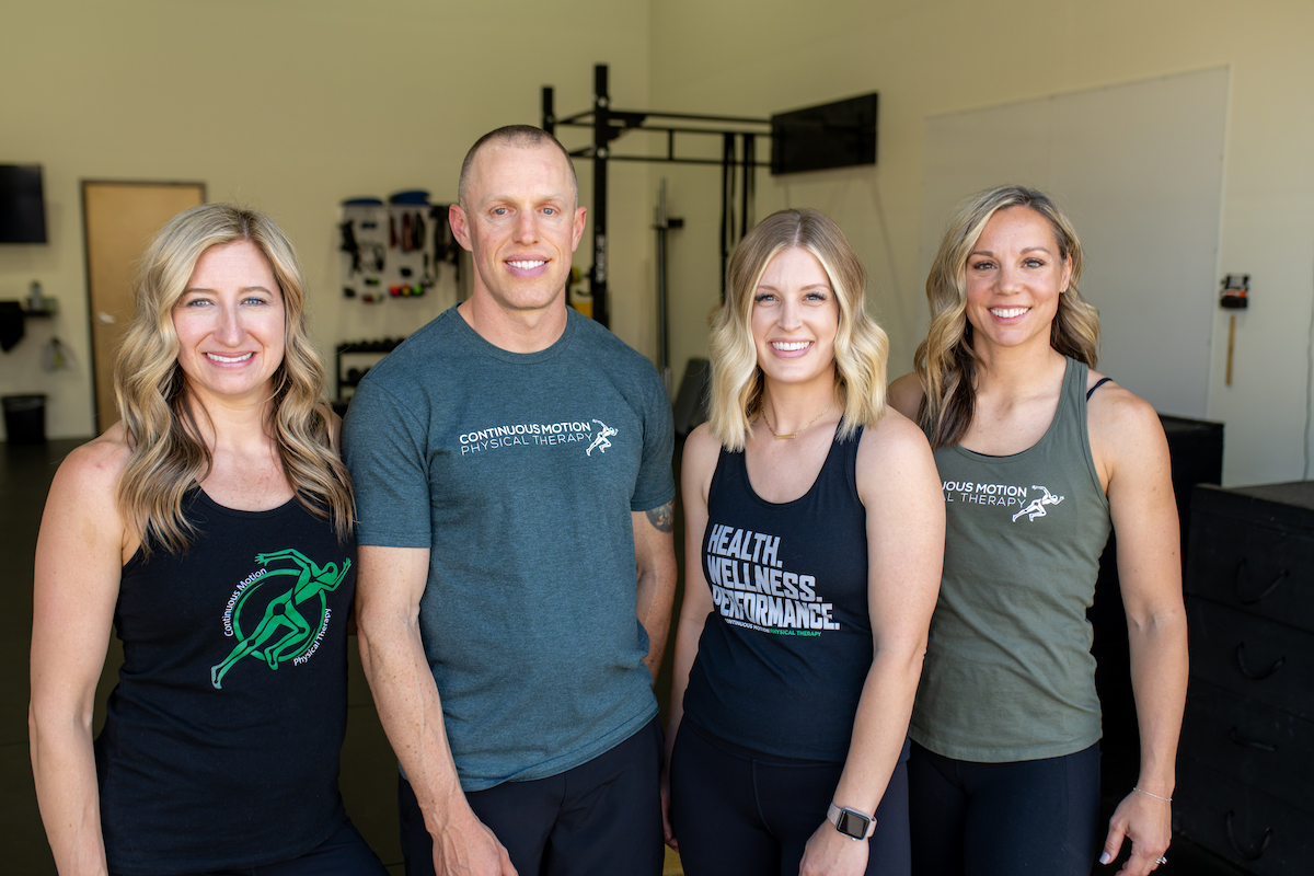 Four people posing for a photo in a gym.