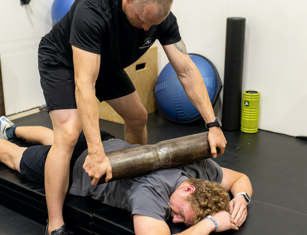 A man is laying down on a mat with a rolled up towel.
