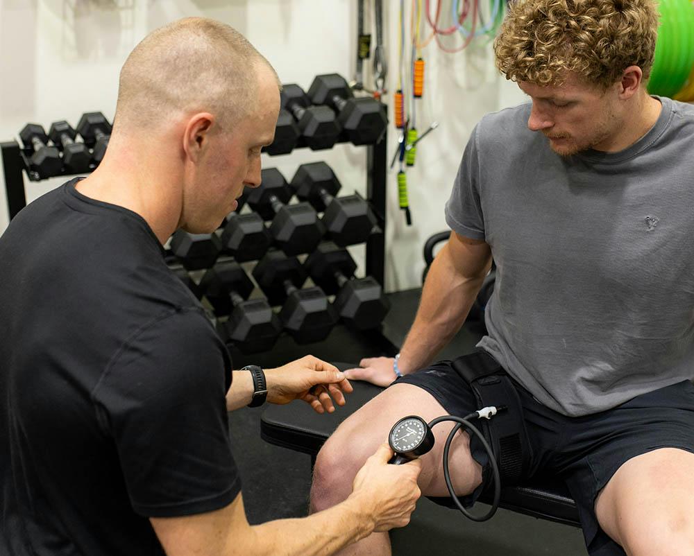 A man sitting on a bench in a gym with a stethoscope.