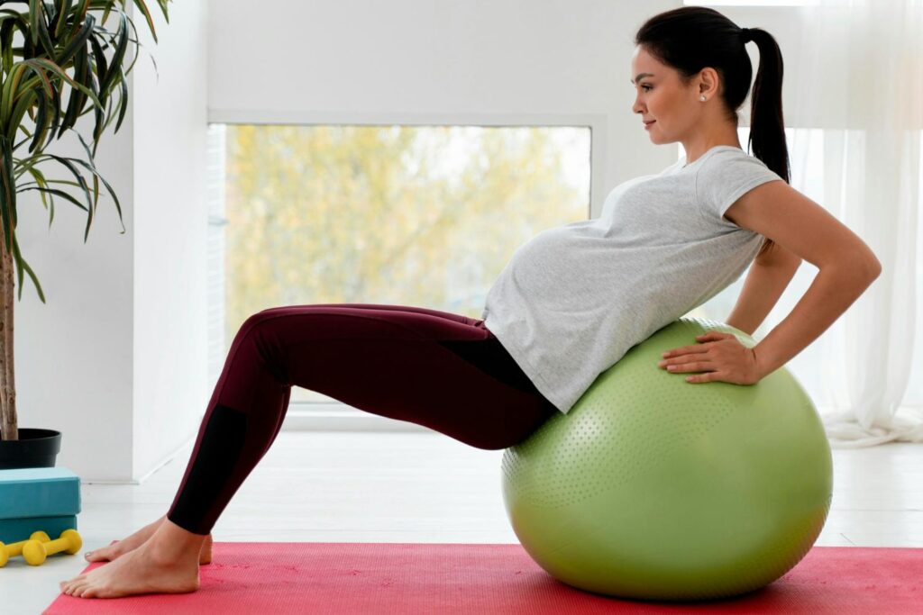 A pregnant woman doing yoga on an exercise ball.